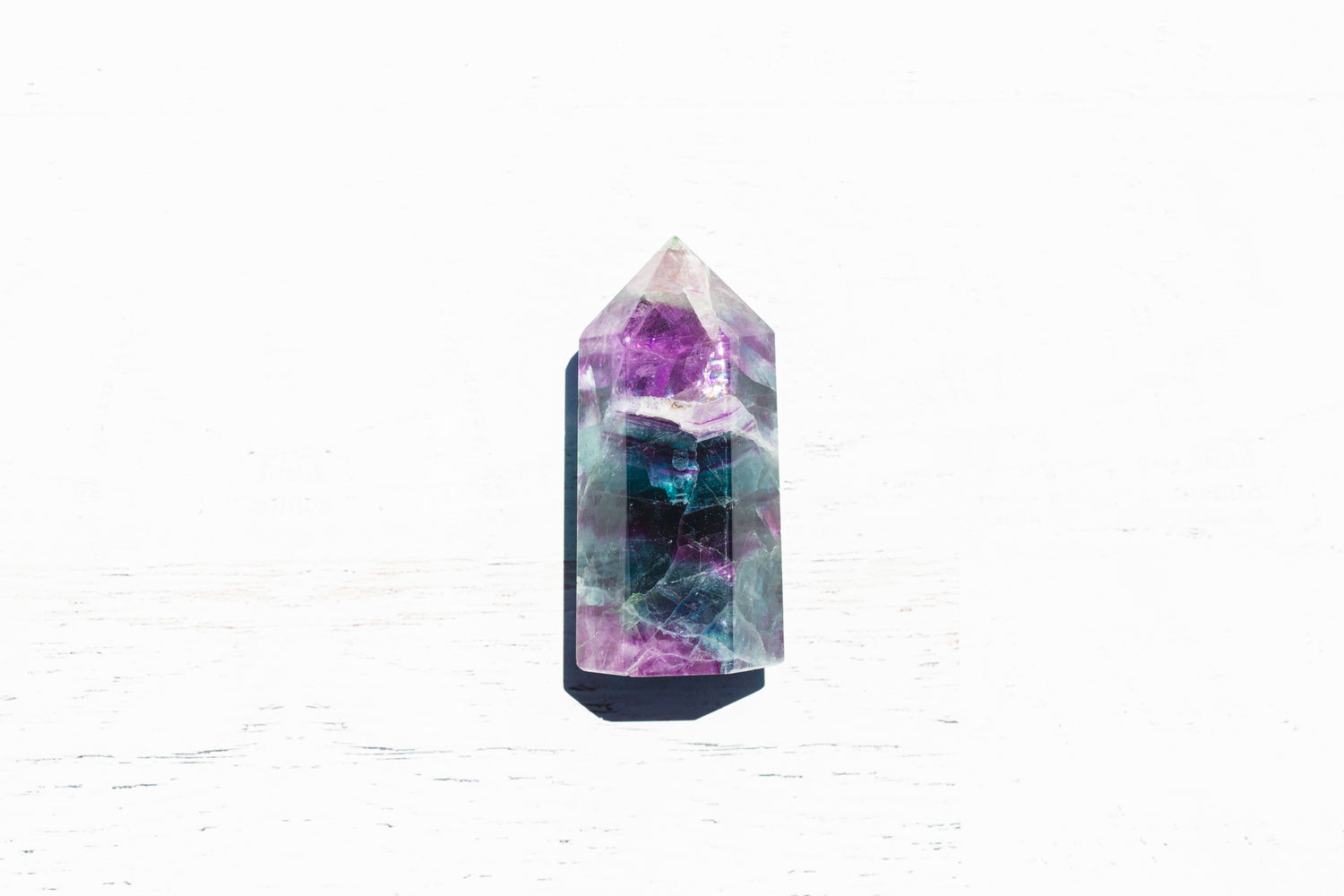 Purple and aqua fluorite tower point on a white background